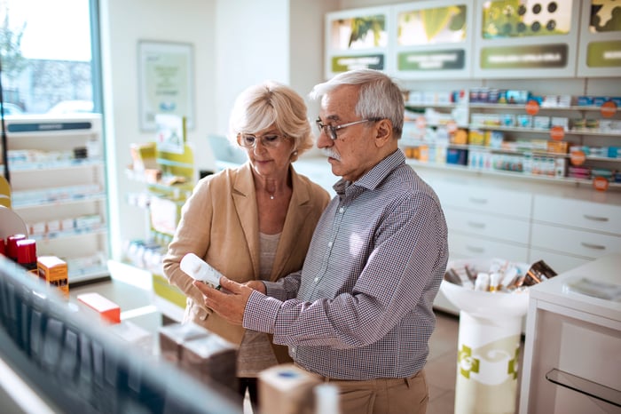 Two people looking at a pill bottle in a store.