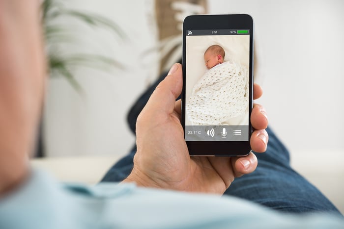 Parent looks at their baby on a smart phone while the child is sleeping.