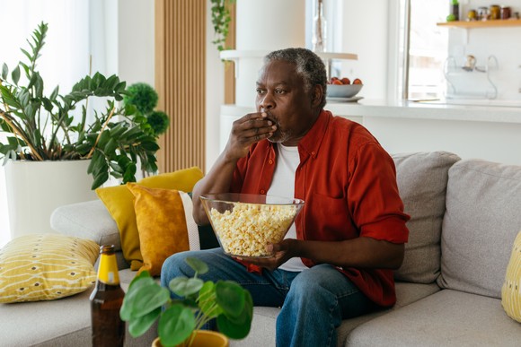 A person watching tv and eating popcorn.