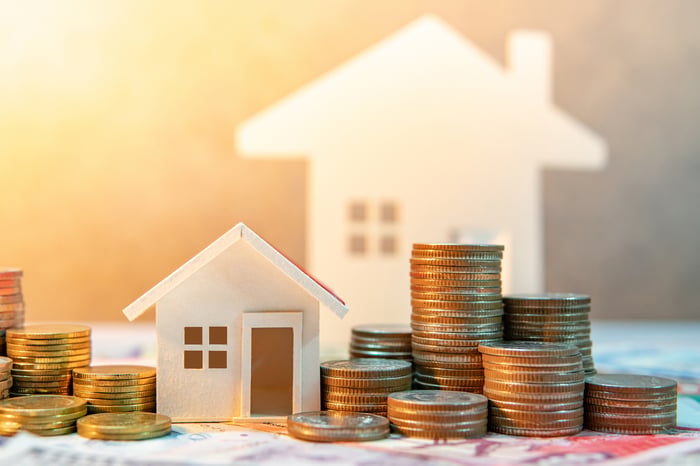 Stacks of coins next to small houses.