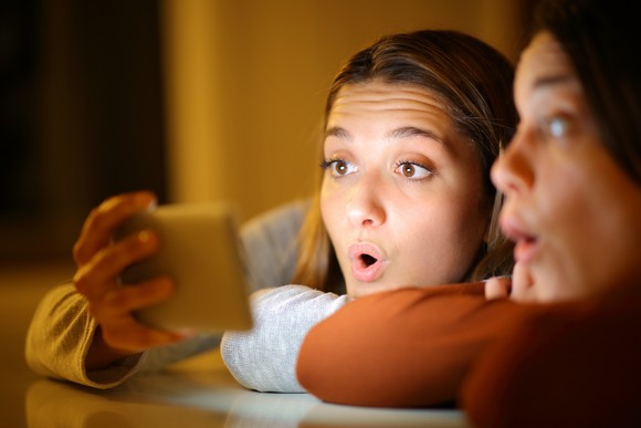 People are surprised as they watch a show streamed on to a mobile phone.