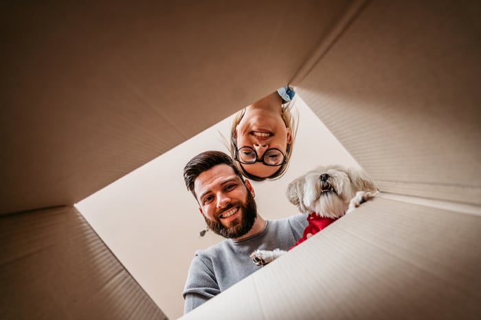 Two people looking into a box with their dog.