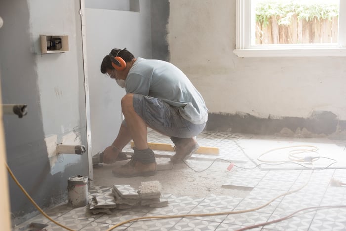 A person installing floor tiles.