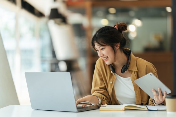 A person looking at a laptop and smiling.