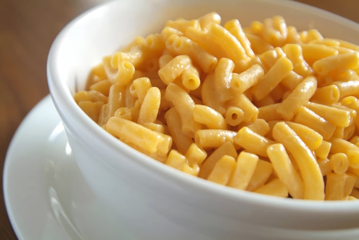 A bowl of macaroni and cheese set on a table. 