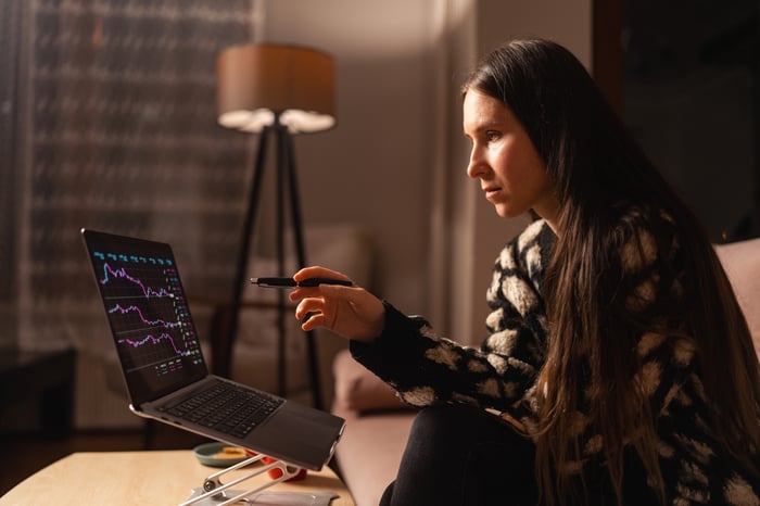 Investor looking at a stock chart on a laptop in a home office.