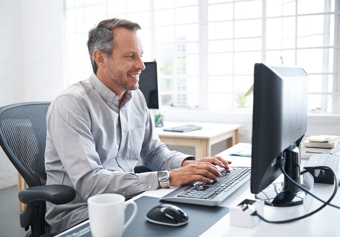 A smiling person at a computer.