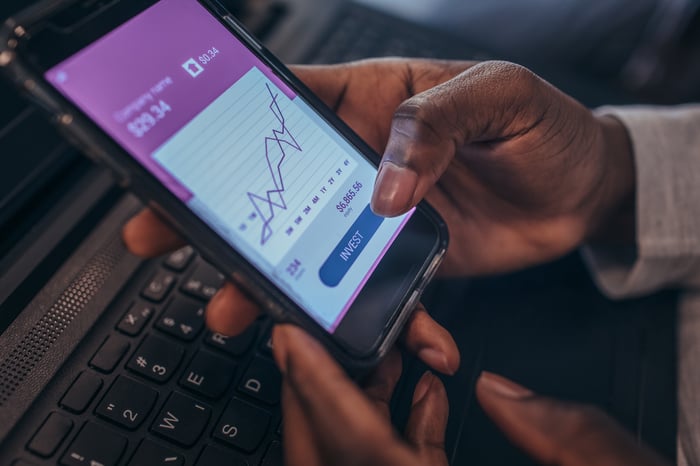 A person investing in stocks using a mobile application.