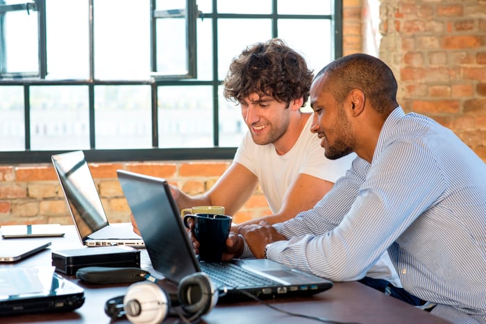 Two people working on their computers in a shared space.