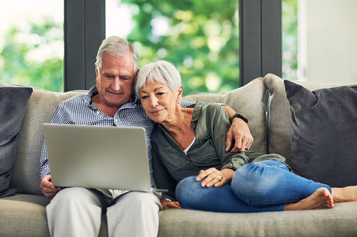 Two people on a couch looking at a laptop.