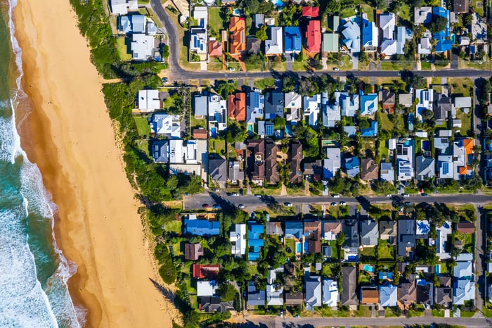 An aerial photo of dozens of houses and the beach in a coastal suburb.