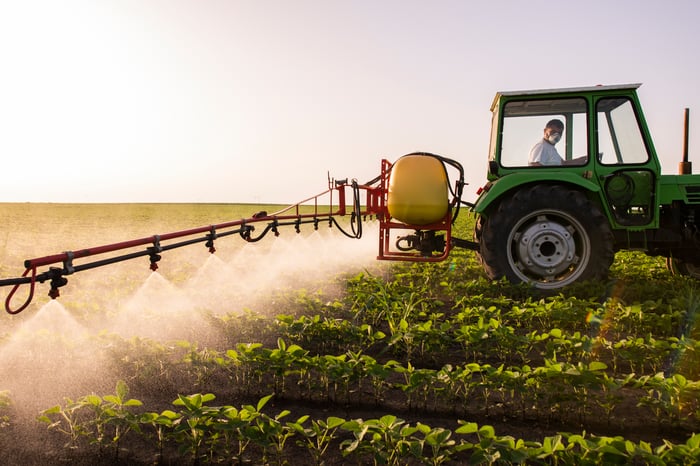 A person in a tractor spraying fertilizers on a soy field.