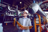 engineer looks at industrial plant while holding folder