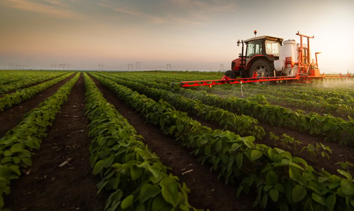 Tractor and sprayer farming a crop field.