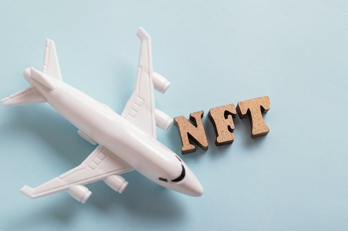 Model white airplane beside the letters NFT on a pale blue background.