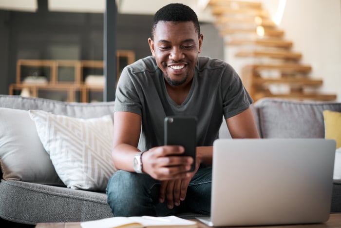 A person sitting on a couch looking at a smartphone.