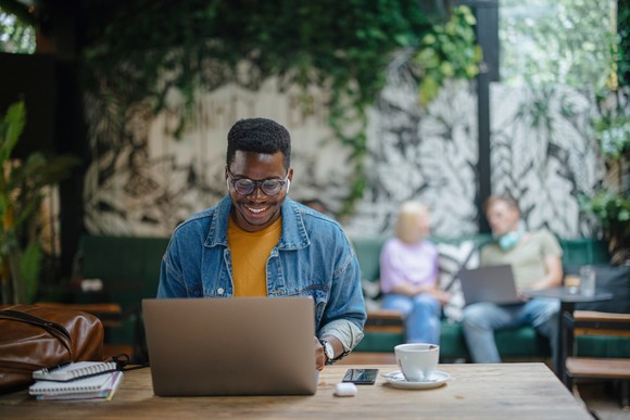 Individual retail investor checks in on their stocks on laptop at a cafe.