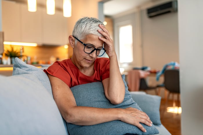 A person on a couch holding their head.