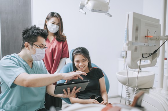 Dentist showing something to a patient on a tablet.