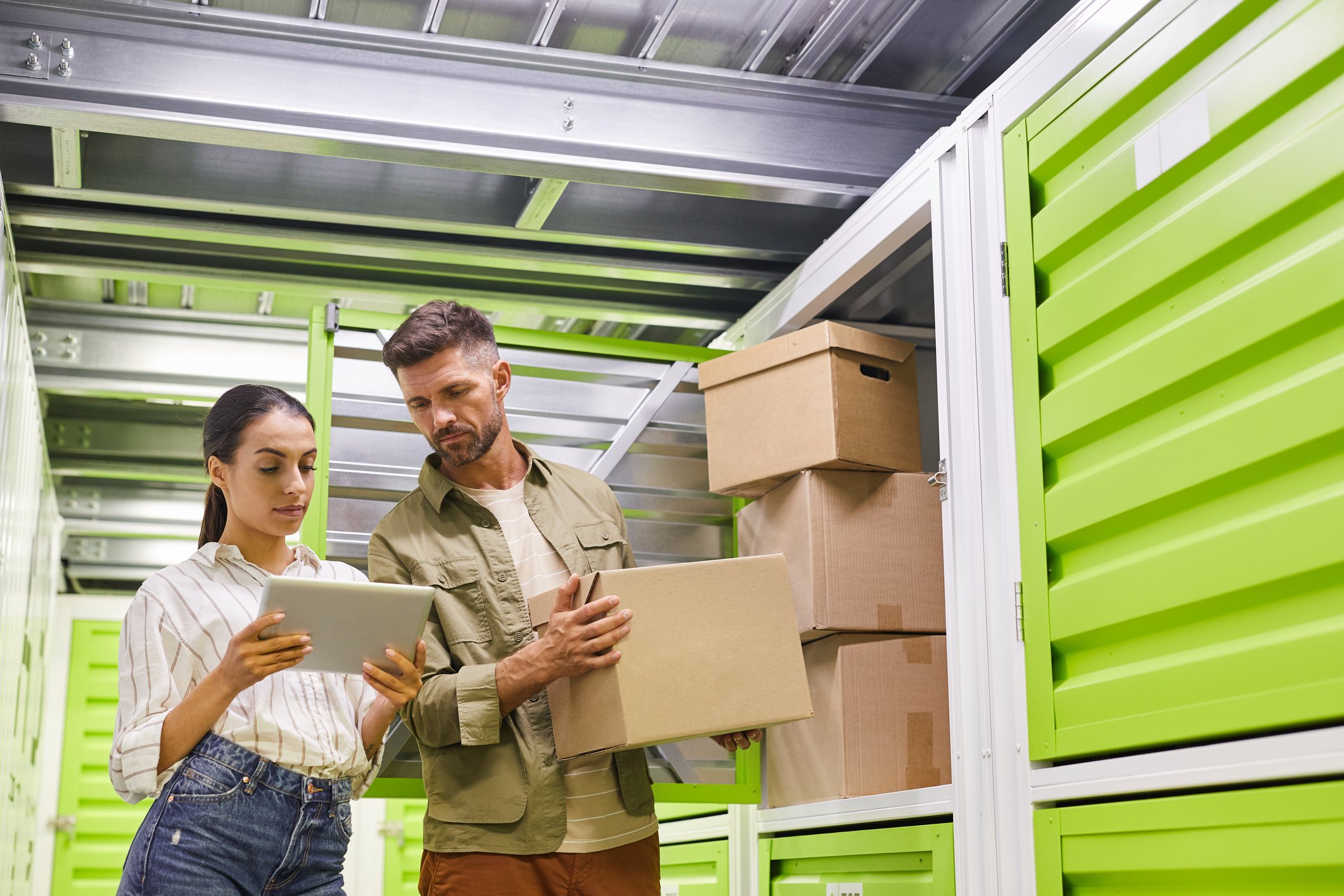 People looking at a tablet while putting stuff in a self-storage unit.