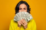 Young Woman holding a lot of money -- GettyImages-1249955556