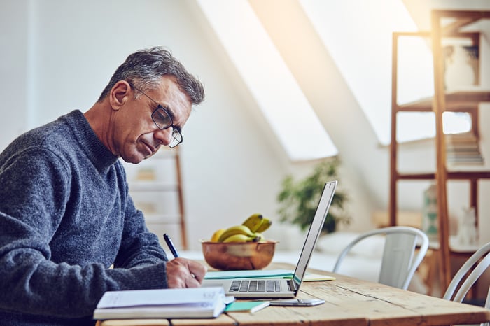 A person taking notes at a laptop.