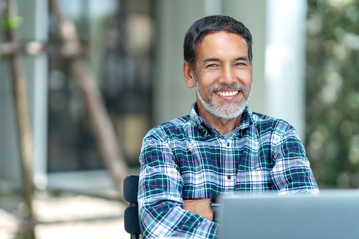 A smiling person at a laptop.