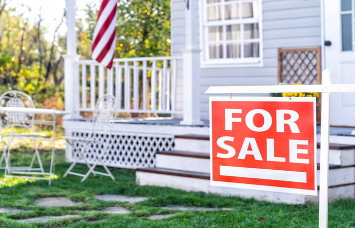 A house with a for sale in front of it.