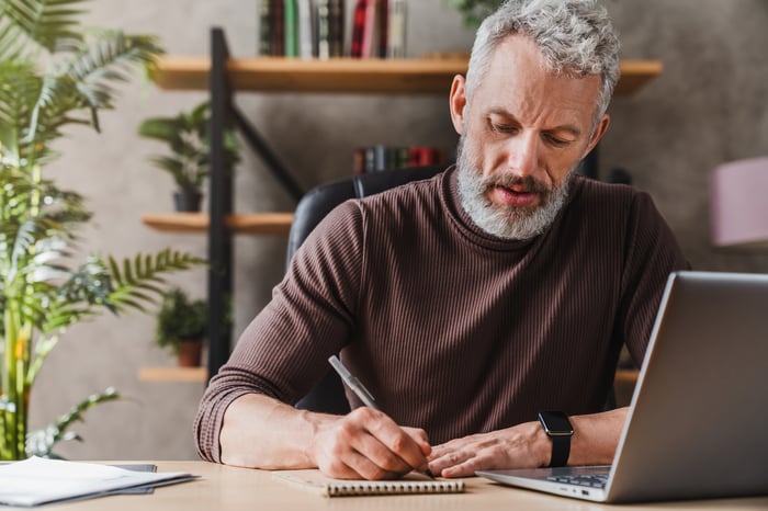 A person at a laptop taking notes.