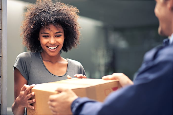 A smiling person accepting a package delivery.