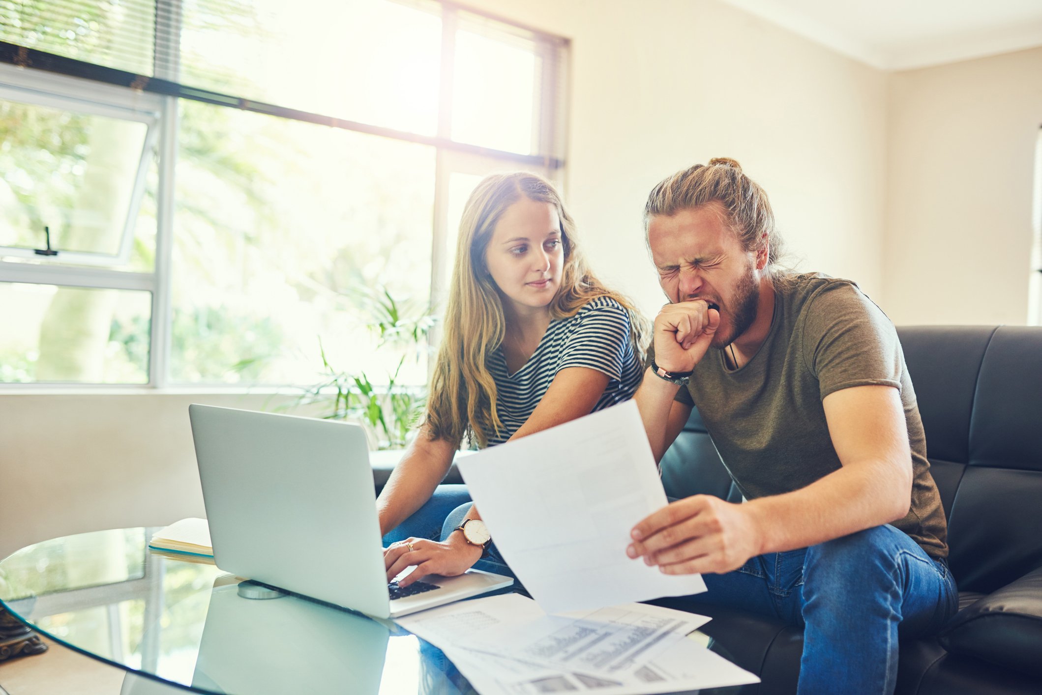 two people looking at documentation as one of them is yawning