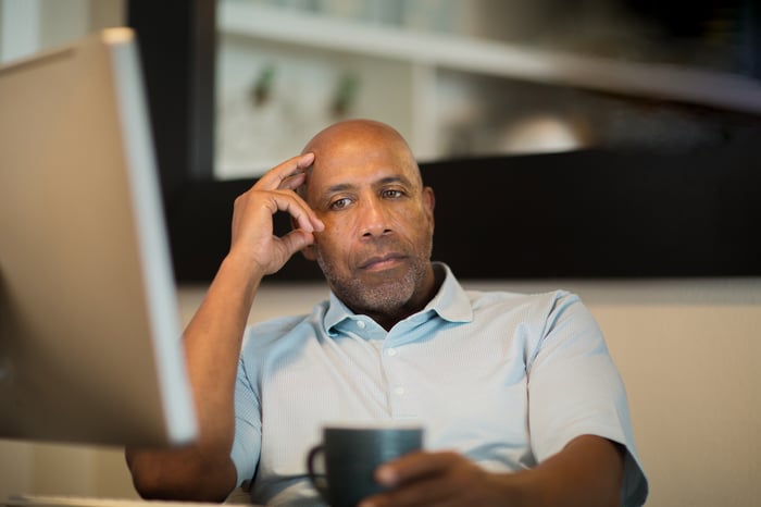 A person appears upset while looking at a computer.