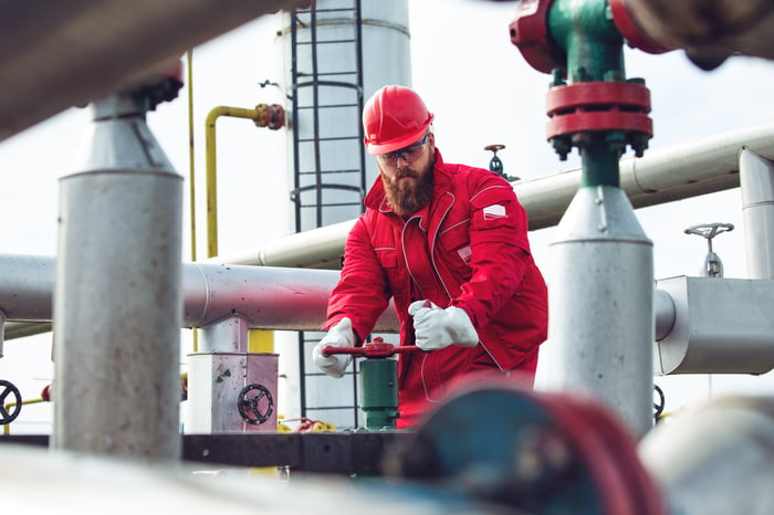 A person in a red protective suit working on an energy pipeline.