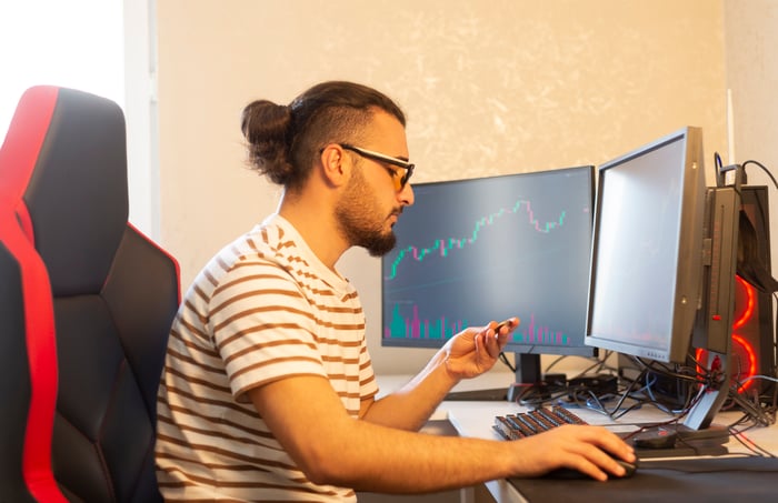 Crypto investor monitors investments on multiple monitors.