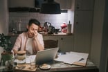 Person at kitchen table looking at laptop.