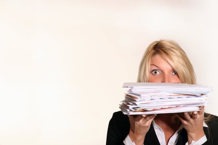 A person holding a stack of mail in front of their face.