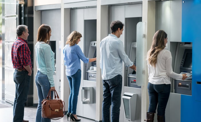 People at ATM machines, depositing and withdrawing money from a bank.