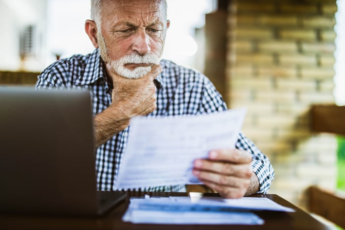 A person with a serious expression holding a document.