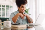A smiling person, looking at laptop.