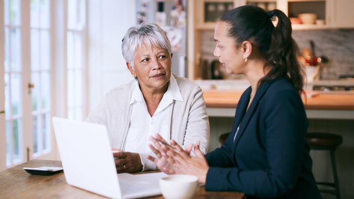 Two adults talking and looking at laptop.