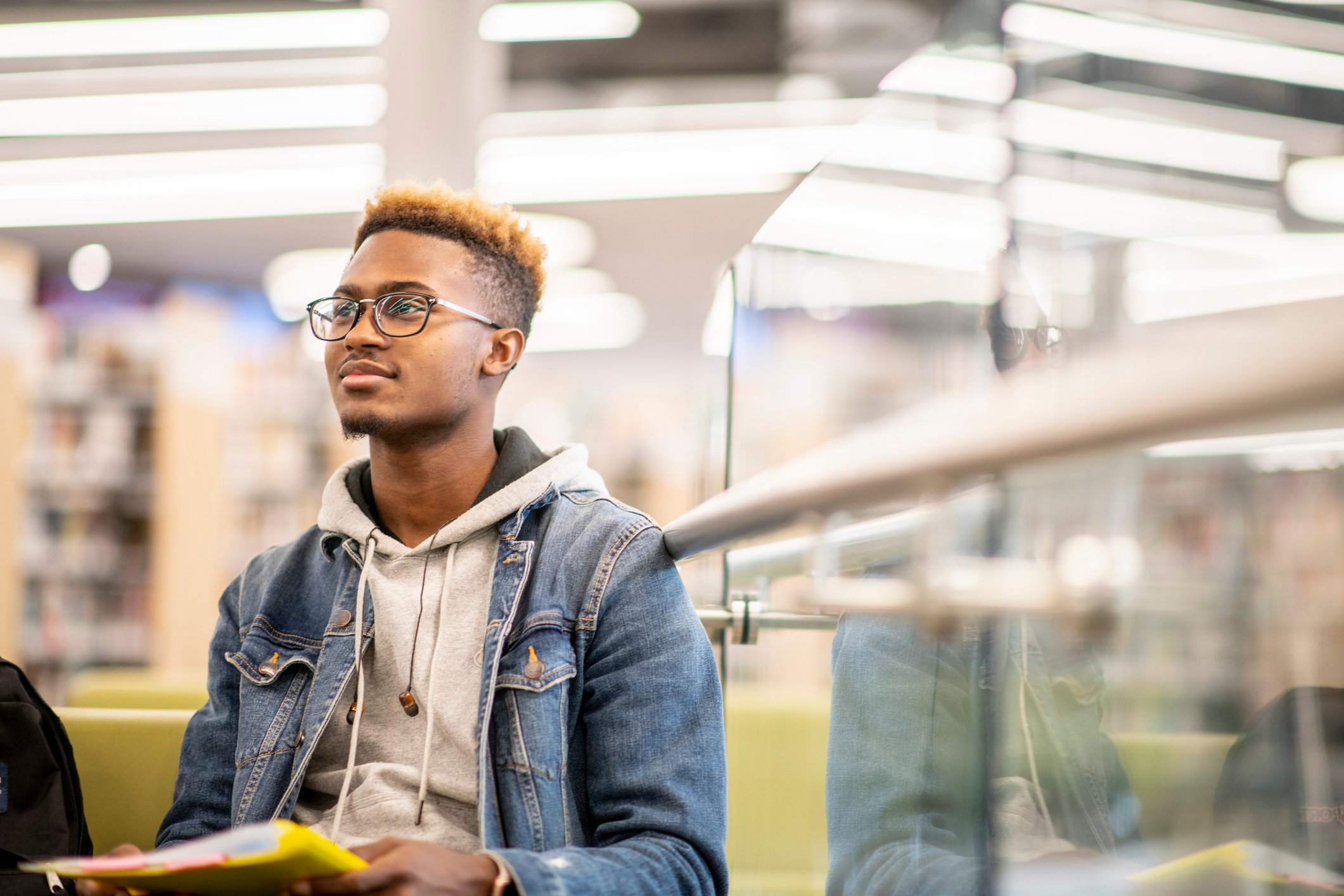 A person looks up and smiles while holding a notebook in a library.