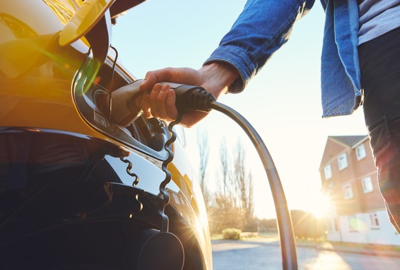 Close-up of person charging yellow electric vehicle.