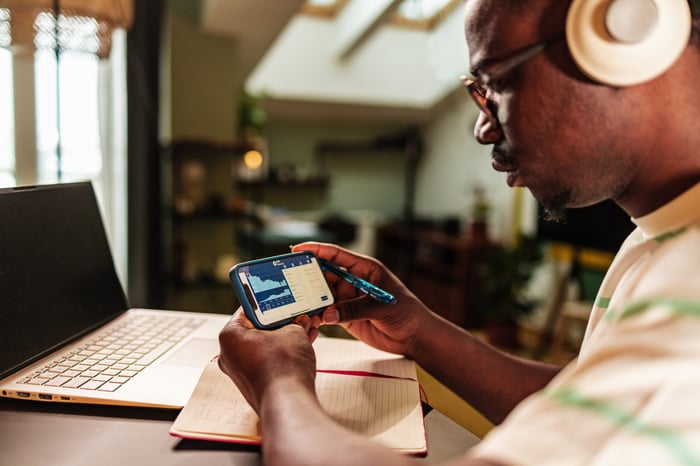 Person wearing headphones studying chart on a smartphone.