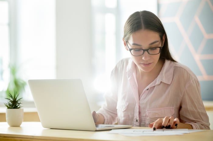 A person at a laptop looking at a document. A person at a laptop looking at a document.