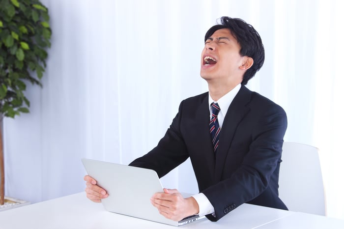 Person holding laptop looking upset.