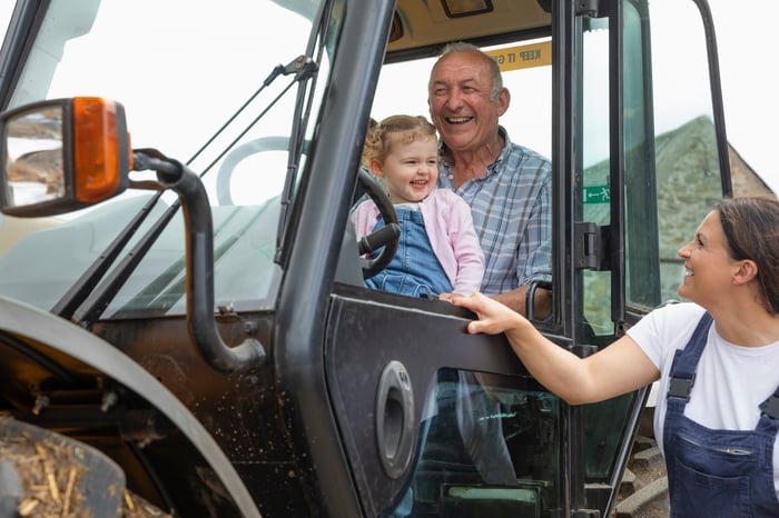 A family smiles while riding in the cab of a tractor.