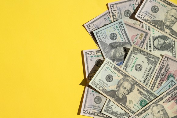 Scattered U.S. dollars against a yellow background.