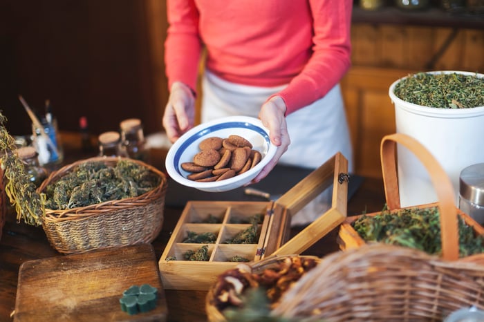 Person holding a batch of cookies over a table of cannabis flower product.