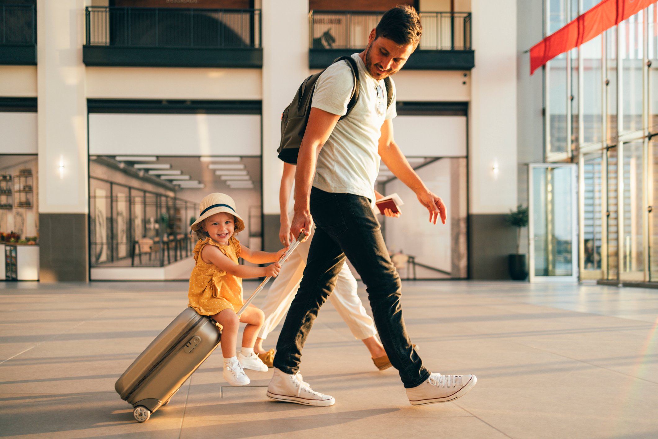 A person pulling a suitcase with a smiling child sitting on it
