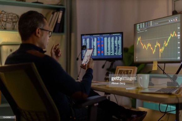 Person looking at stock charts on computer monitors.